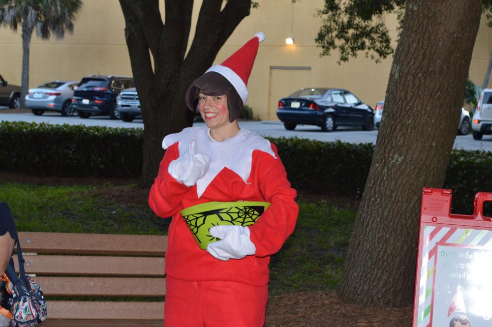 Woman in red elf costume gives a thumbs up and smiles to camera